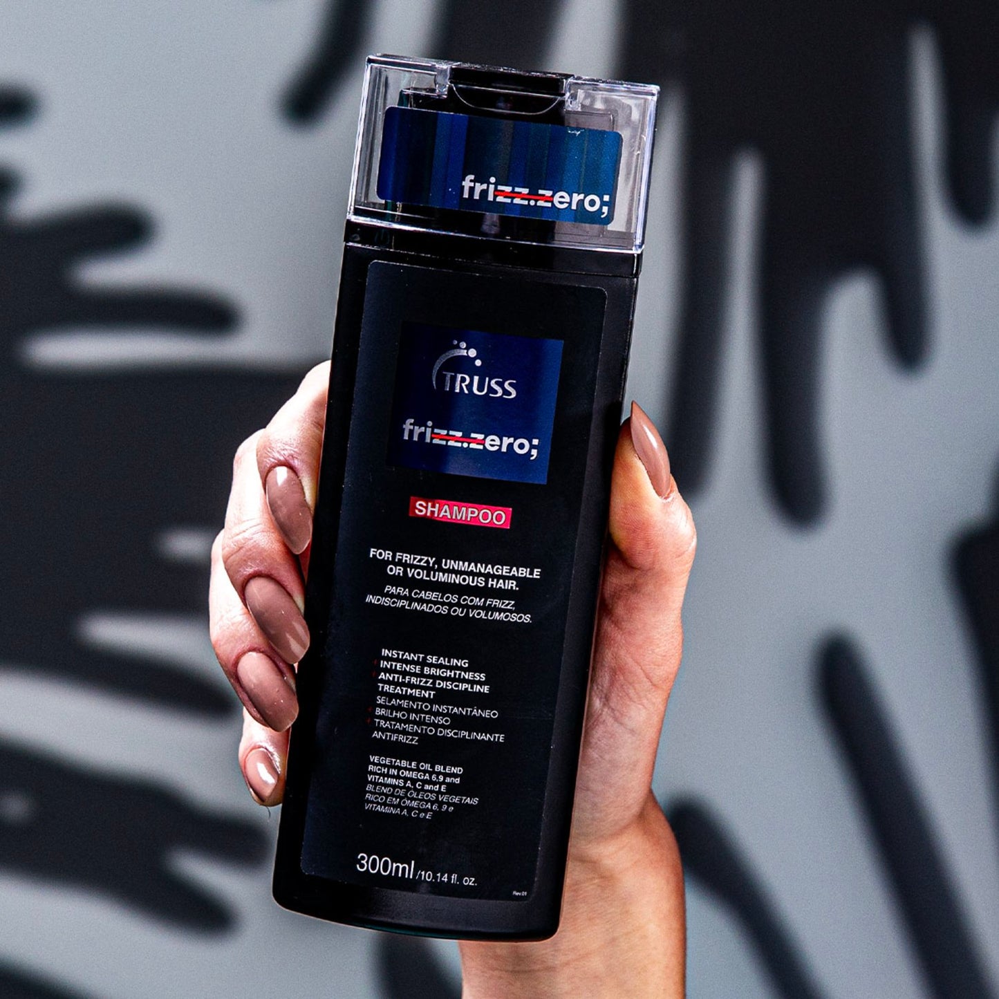 A imagem mostra um produto para cuidados capilares da marca Frizz Zero. É um shampoo específico para cabelos frizados, incontroláveis ou volumosos. O frasco plástico tem coloração preta com detalhes em azul, exibindo o logotipo da marca "Frizz Zero".