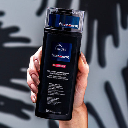 A imagem mostra um produto para cuidados capilares da marca Frizz Zero. É um shampoo específico para cabelos frizados, incontroláveis ou volumosos. O frasco plástico tem coloração preta com detalhes em azul, exibindo o logotipo da marca "Frizz Zero".